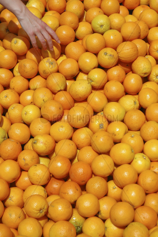 Frauenhand greift in grosse Apfelsinenkiste