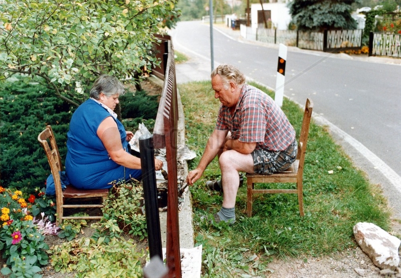 Ehepaar streicht Gartenzaun von unterschiedlichen Seiten