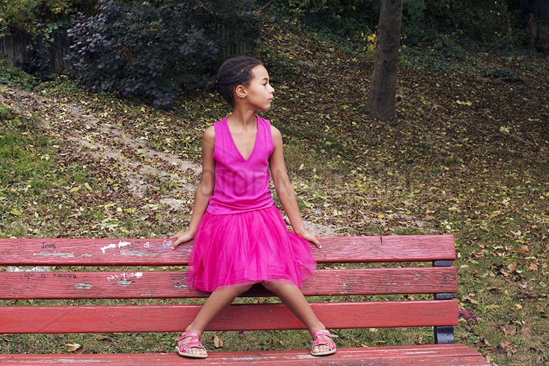 Girl sitting alone on park bench,  looking away in thought