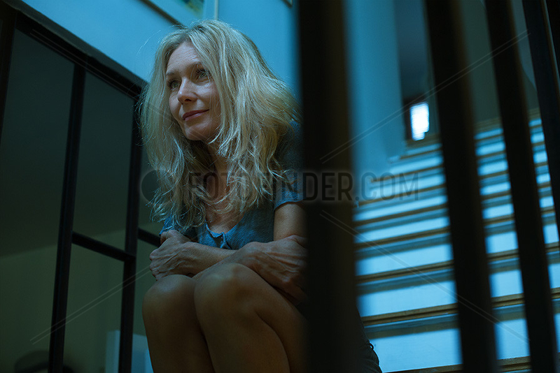 Mature woman sitting on stairs,  looking away in thought
