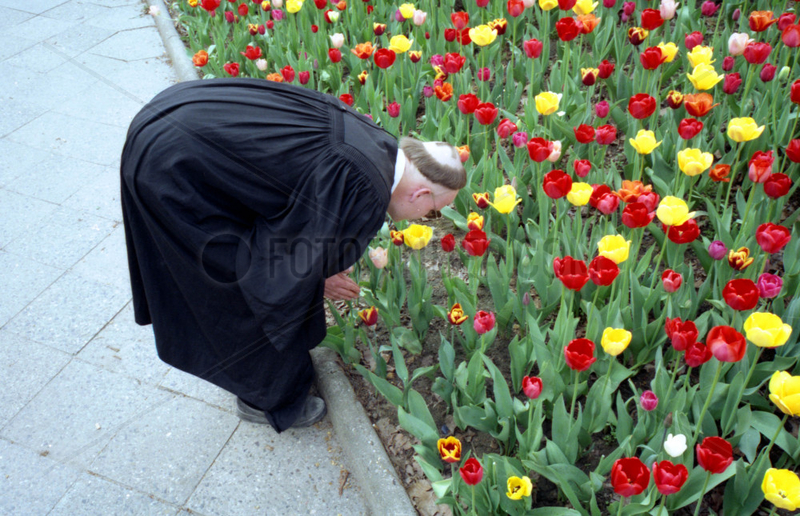 Geistlicher riecht an Blumen