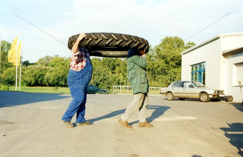 zwei kopflose Maenner tragen einen grossen Reifen