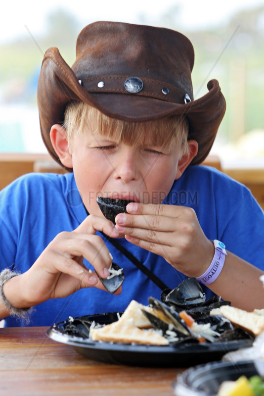 Saint Petersburg,  USA,  Junge mit Cowboyhut isst frische Miesmuscheln