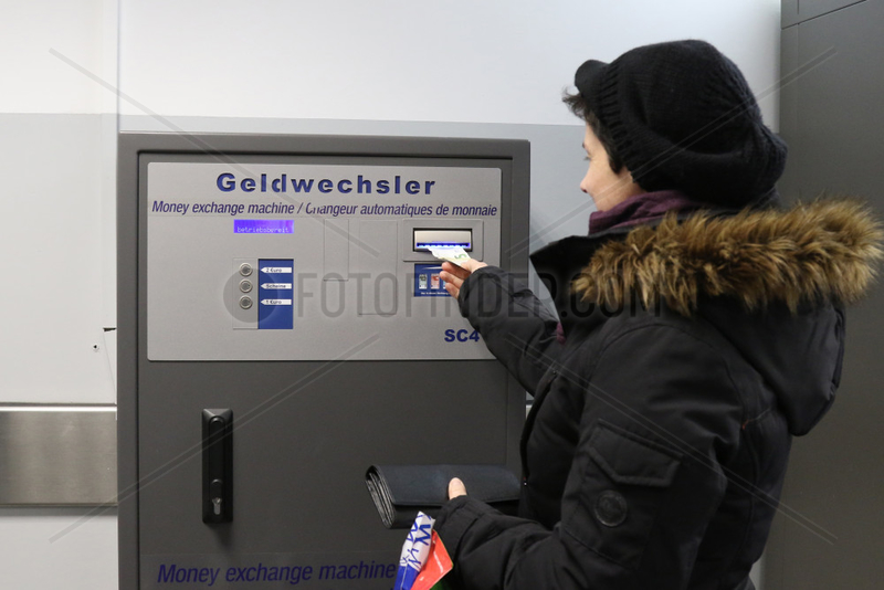 Berlin,  Deutschland,  Frau schiebt einen Geldschein in einen Geldwechselautomat