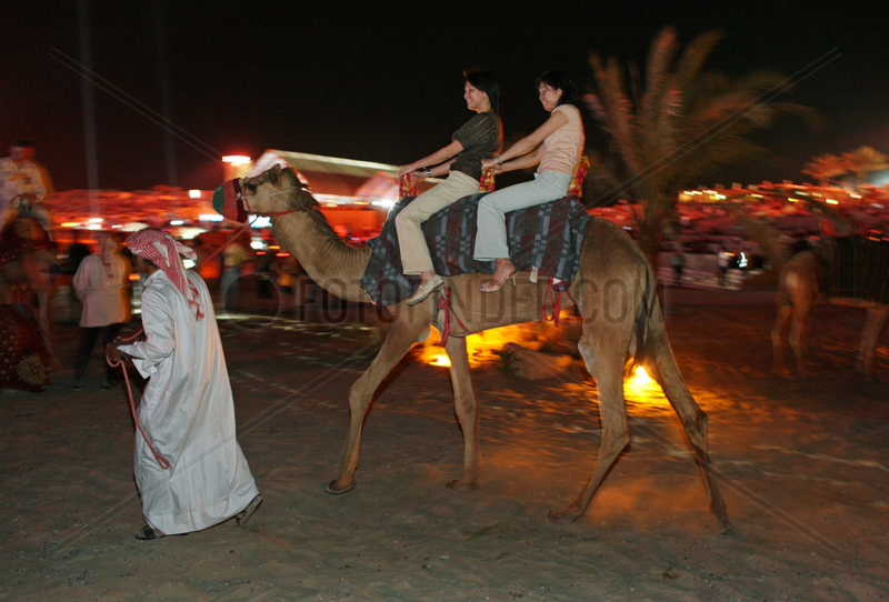 Dubai,  Vereinigte Arabische Emirate,  Frauen reiten auf einem Kamel