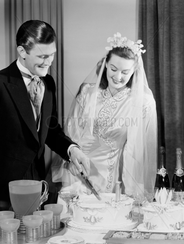 Bride and groom cutting their wedding cake,  c 1949.