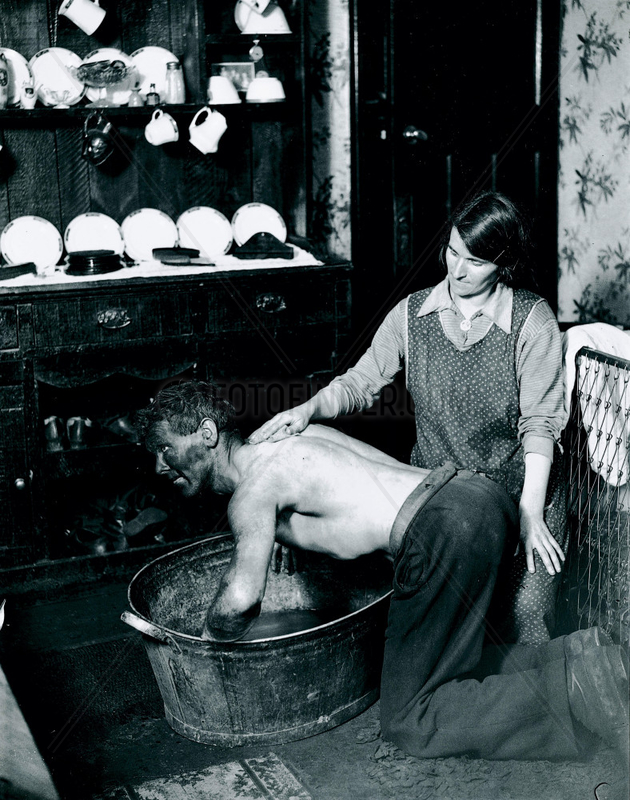 A Welsh miner's wife washing her husband after work,  June 1931.