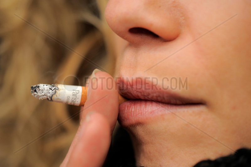 Junge Frau raucht eine Zigarette,  Schaerfe auf Zigarette.