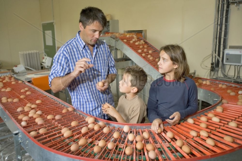 Landwirt,  der sich bei seinen Kindern Eier auf dem Teppich zeigt