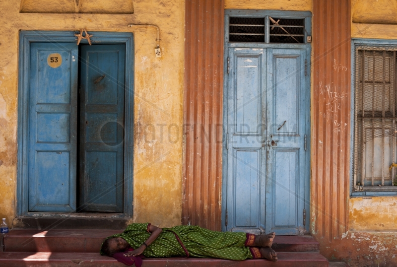 Crippled woman asleep in front of a door not India