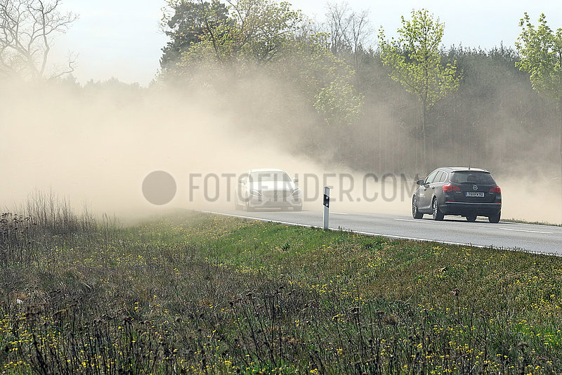 Doebrichau,  Deutschland,  Autos fahren auf einer Landstrasse durch eine bei der Feldarbeit entstandene Staubwolke