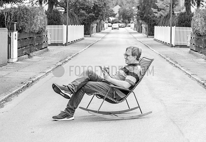 Mann im Schaukelstuhl auf der Strasse,  Muenchen,  August 2020