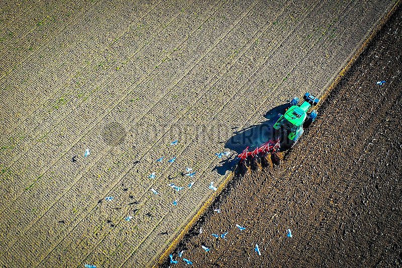 Drohnenaufnahme Bauer beim Pfluegen eines Ackers