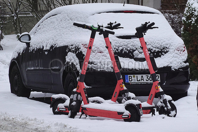 Berlin,  Deutschland,  E-Roller des Anbieters voiscooters stehen mit Schnee bedeckt auf einer Strasse