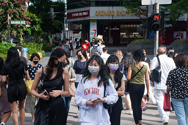 Singapur,  Republik Singapur,  Fussgaenger mit Mundschutz gehen die Orchard Road entlang