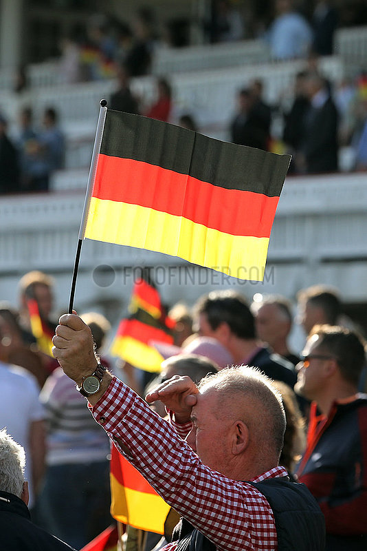Hoppegarten,  Deutschland,  Mann haelt am Tag der Deutschen Einheit die Nationalfahne hoch