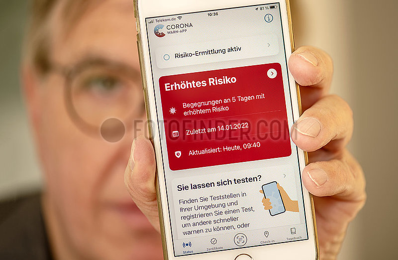 Mann,  Ü60,  zeigt Corona Warn App auf seinem Smartphone,  Warnstufe Rot,  5 Risikobegegnungen in den letzten Tagen,  München,  Januar 2022