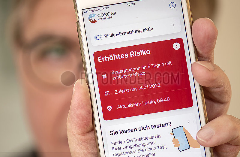 Mann,  Ü60,  zeigt Corona Warn App auf seinem Smartphone,  Warnstufe Rot,  5 Risikobegegnungen in den letzten Tagen,  München,  Januar 2022