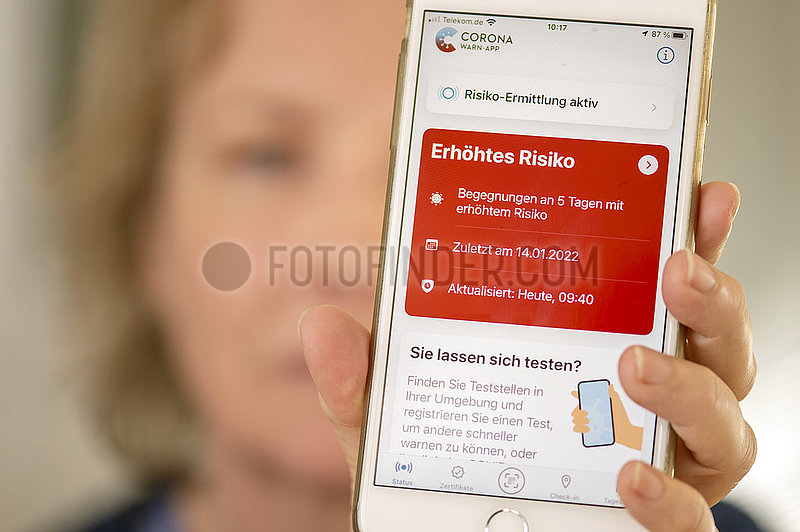 Frau,  Ü60,  zeigt Corona Warn App auf ihrem Smartphone,  Warnstufe Rot,  5 Risikobegegnungen in den letzten Tagen,  München,  Januar 2022