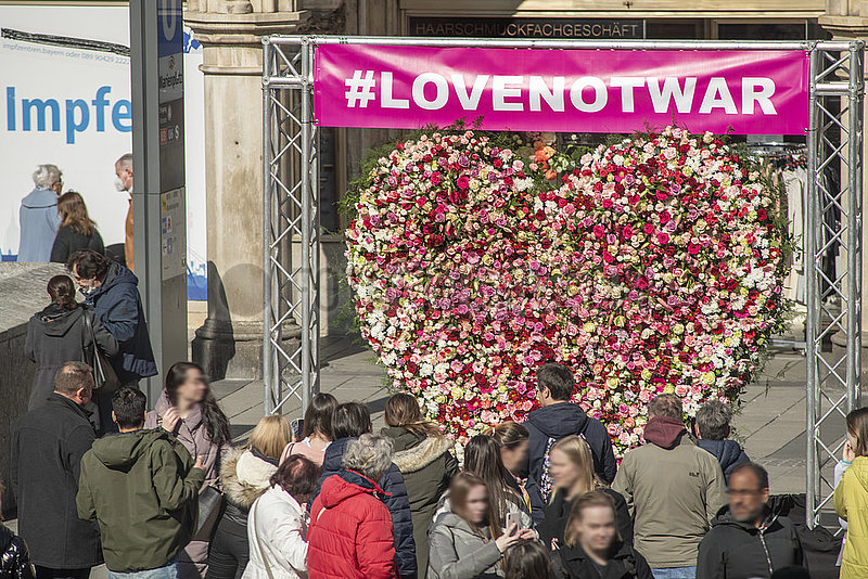 Blumenherz unter dem Hashtag lovenotwar auf dem Münchner Marienplatz,  europaweite Friedensaktion von Floristen,  daneben Impfzentrum,  München,  12. März 2022