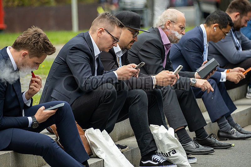 Deutschland,  Hannover - Hannover-Messe,  Geschaeftsleute aus unterschiedlichen Laendern sitzen konzentriert mit ihren smartfones