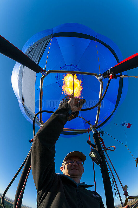 Frankreich,  Essonne (91),  Heißluftballonpilot,  der seinen Gasbrenner betreibt