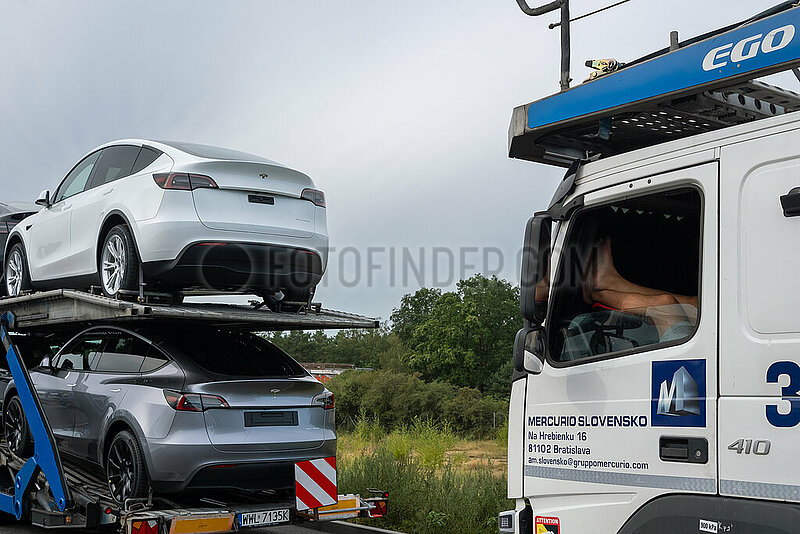 Deutschland,  Gruenheide - Teslas auf Autotransporter vor der Tesla Gigafactory Berlin-Brandenburg,  Beine eines pausierenden LKW-Fahrers aus der Slowakei