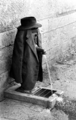 Mantel mit Hut ueber Pumpe