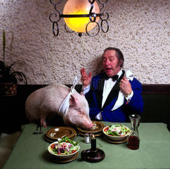 Mann und Schwein essen zusammen am Tisch