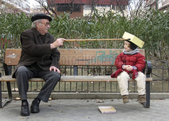 Opa und Enkel spielen auf einer Parkbank