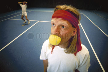 Tennisspieler faengt Ball mit dem Mund