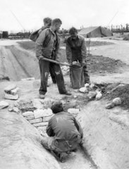Vier Jungen bauen einen Uebergang von einem Graben