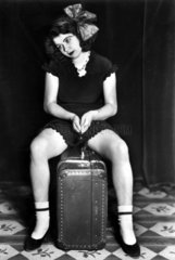Junge Frau sitzt auf Koffer