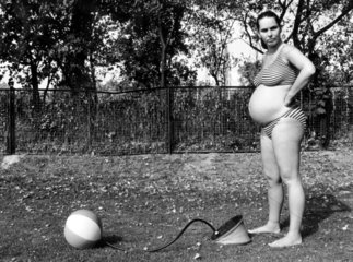 Schwangere Frau pustet Ball auf