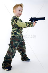 kleiner Junge in Tarnkleidung zielt mit grosser Waffe