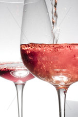 In einem Weinglas wird Rosé eingegossen