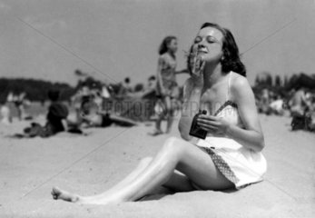 Frau am Strand cremt sich ein