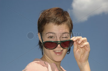 Frau zwinkert hinter Sonnenbrille - Auge zukneifen