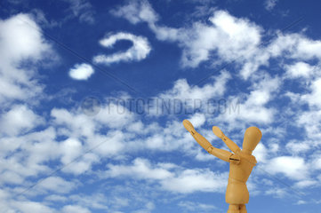 Holzfigur schaut in den Himmel und sieht Fragezeichen