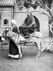 verschleierte Frau sitzt auf Esel