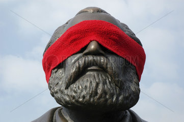 Augen von Karl-Marx mit einem roten Schal verbunden
