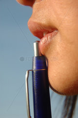 Frau mit Kugelschreiber an den Lippen