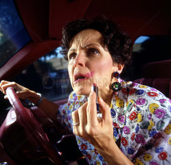 Frau schmiert Lippenstift beim Fahren