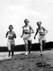 Drei Frauen rennen am Strand
