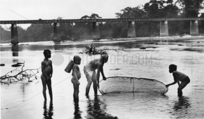 Afrikaner fischen in einem Fluss vor Bruecke