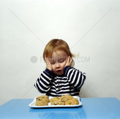 Kleines Kind sitzt vor einem Kuchen