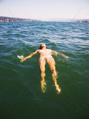 nackte Frau laesst sich im Wasser treiben