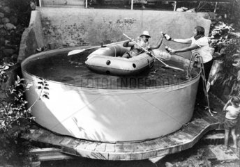 Mann mit Schwimmweste in Schlauchboot im Planschbecken