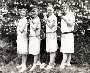 Vier Frauen posieren mit Tennisschlaegern
