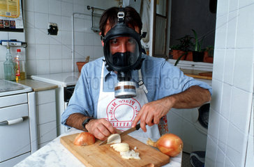 Mann mit Gasmaske beim Zwiebelschneiden
